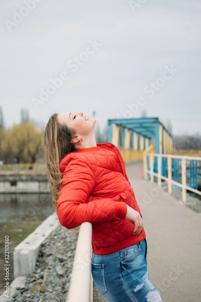 Fototapeta Embrace being single, Art of Being Happily Single. Woman in red jacket walks by the river alone. calm scene