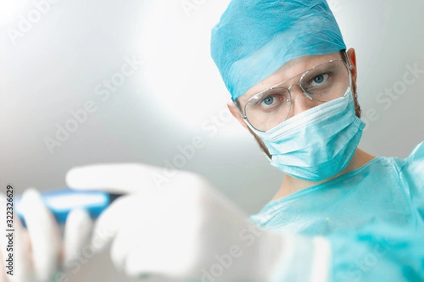 Fototapeta assistant passes the instrument to the surgeon in the operating room