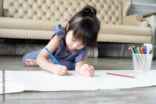 Fototapeta Beautiful Asian child girl lying and drawing with color pencils at home