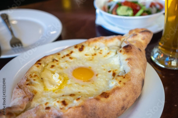 Fototapeta Khachapuri in Georgian restaurant - Georgian national cheese bread product, pie stuffed with cheese and eggs - Adjara Khachapuri is a famous dish from Georgia