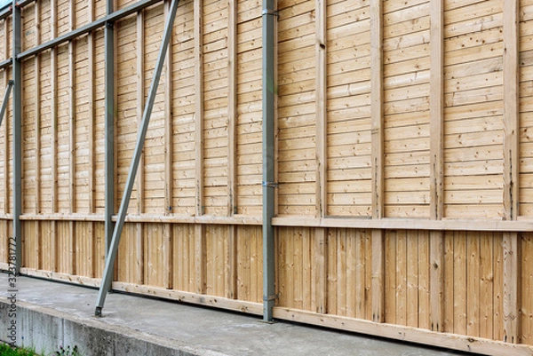 Fototapeta Tall wooden wall in outdoors with metal parts.