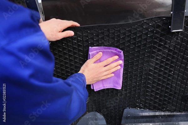 Fototapeta Worker wiping automobile floor mat at car wash, closeup