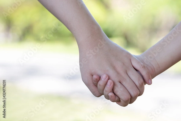 Obraz Mother holding a hand of child in garden. Using for family,safety and lead concept.