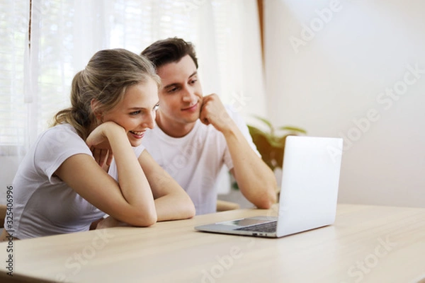 Fototapeta Happy couple lover talking and waving hand in a video conference on line with a laptop for contact friendship at home.