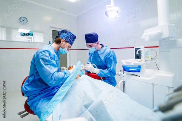 Fototapeta Medicine, dentistry and healthcare concept. Dentists treating patient`s teeth at dental clinic office.