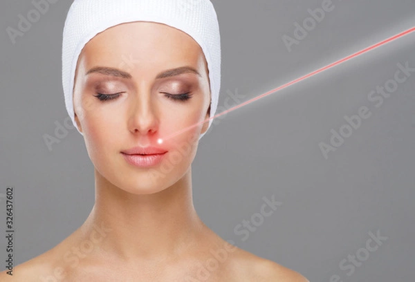 Fototapeta Doctor removing birthmarks with a laser ray. Beautiful face of a young woman. Mole removal, plastic surgery, skin lifting and aesthetic medicine.