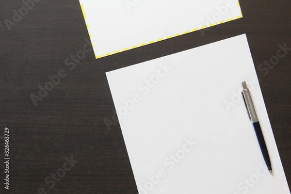 Fototapeta Template of white paper with pen and envelope on dark wenge color wooden background.