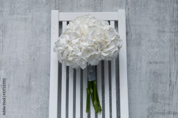 Fototapeta Wedding bouquet of white hydrangeas lies on a white chair