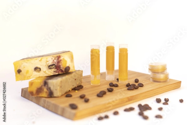 Fototapeta Natural cosmetic on the wooden board. The shadow of the fern. Coffee beans. Hand made soap and lip balm. White background