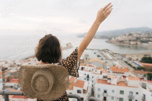 Fototapeta young female traveler stands on top of castle, city view, Peniscola Spain