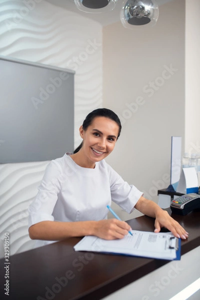 Fototapeta Cheerful manager of beauty clinic smiling while greeting clients