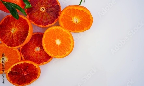 Fototapeta Platter of orange and mandarosa red clementines cut in half on a white platter