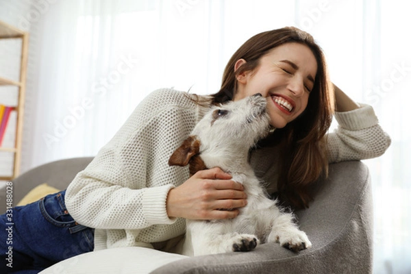 Fototapeta Young woman with her cute Jack Russell Terrier on sofa at home. Lovely pet