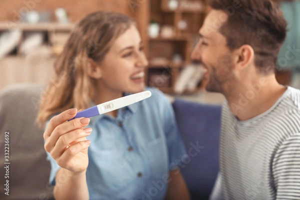 Fototapeta Happy young couple with pregnancy test at home