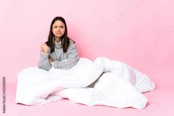 Obraz Young mixed race woman wearing pijama sitting on the floor with unhappy expression