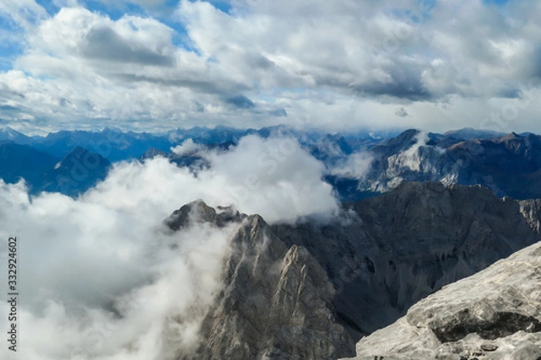 Fototapeta Sharp and rocky mountains range at Austrian-Italian border. There s a path mark on a stone. Serenity and peace. Clouds breaching high mountains. Lots of loose rocks, possibility of landslide