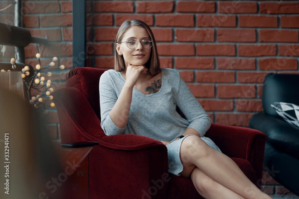 Fototapeta Attractive girl sitting in a red cozy chair