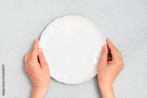 Fototapeta Young woman hands holding white empty plate