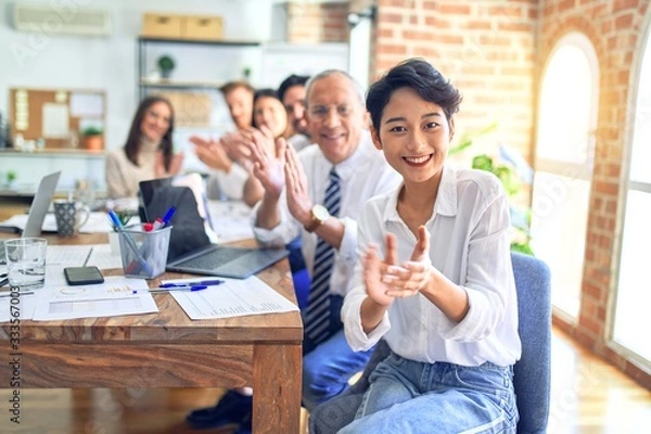 Fototapeta Group of business workers smiling happy and confident. Working together with smile on face looking at the camera applauding at the office