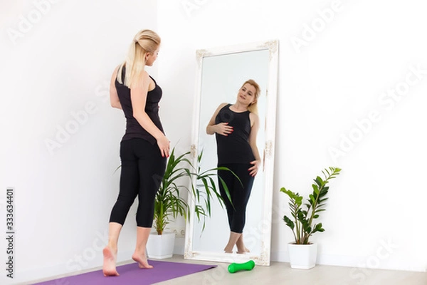 Fototapeta Young woman exercising at home, stretching legs.