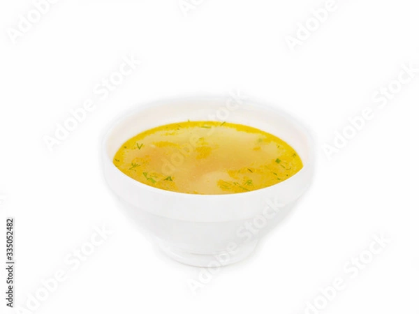 Fototapeta Bowl of golden broth with chopped herbs on a white background side view