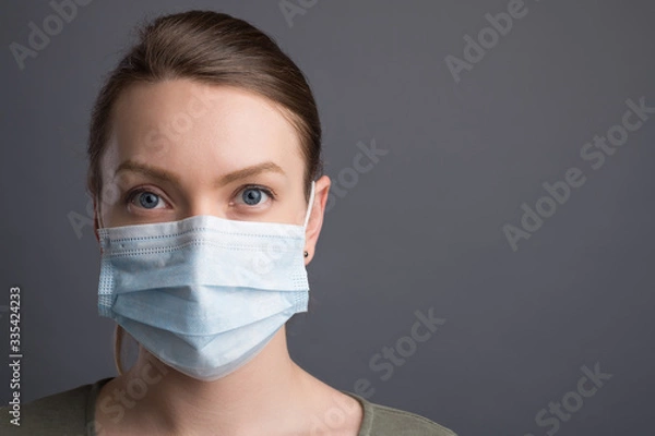 Fototapeta Coronavirus,covid19 girl in a mask on a gray background. The title is about an outbreak of a coronavirus virus in China, an illness. Epidemic and Pandemic: News Headlines and Media