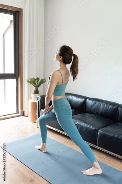 Obraz A young Asian woman doing yoga at home