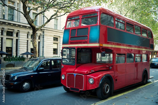 Fototapeta Traditional red double-decker Routemaster bus, introduced in 1956, making its way along an empty summer street in London, UK