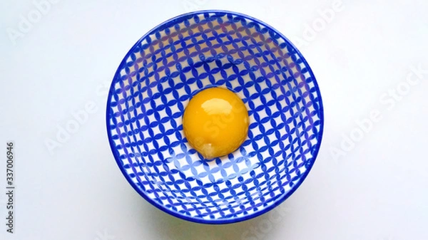 Fototapeta Raw egg yolk in a deep plate with a blue-white pattern