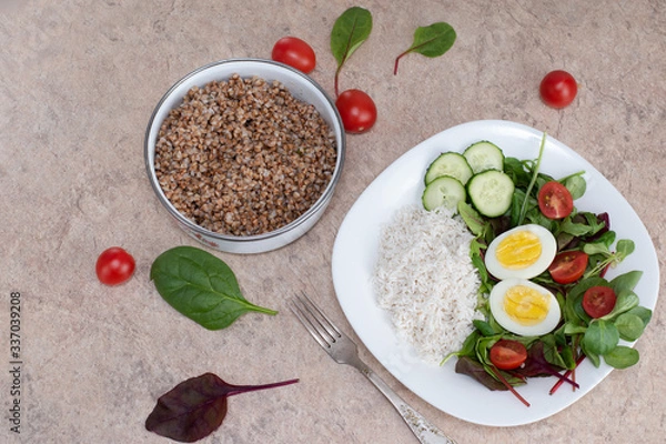 Fototapeta Salad of green vegetables, tomato and rice in a white plate. Rice with vegetables and eggs on a white plate.