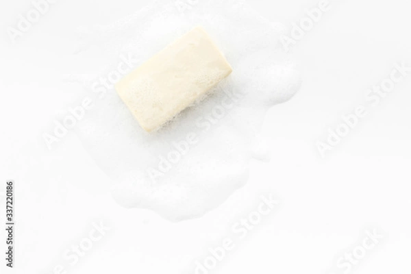 Fototapeta Soap bar with foam on white background top-down copy space