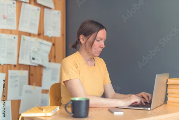 Fototapeta Female freelancer working from home on laptop computer