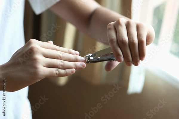 Fototapeta Closeup of a man cutting nails, health care concept