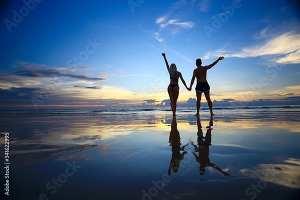 Fototapeta lovers run along the beach / guy and girl run along the summer sea beach, rest on the sea honeymoon