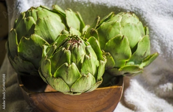 Fototapeta Artichokes close up. Artichoke flowers in rustic wooden bowl. Healthy eating concept, vegetable background, natural eco products. Selective focus image. Copy space.