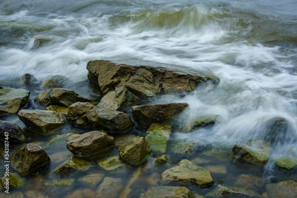 Fototapeta Landscape with waves crashing against the coastal stones at sunrise.