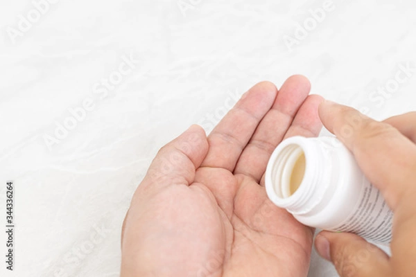 Fototapeta Hands with pills in the box with white background and copy space