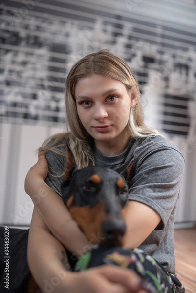 Obraz Portrait of a blonde with a doberman. Girl hugs a dog. Photographed close-up.