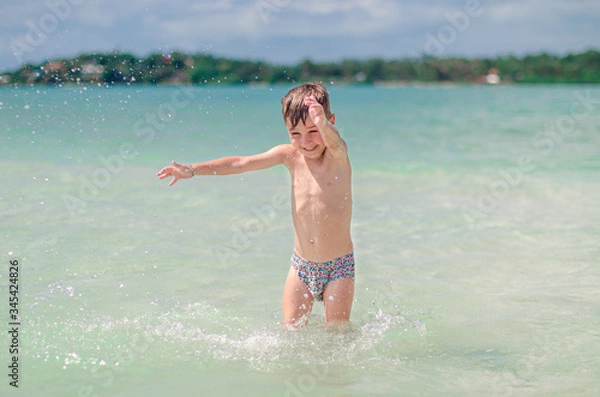 Obraz 
happy child splashes on the ocean. The kid smiles and bathes in the sea. Beautiful coast of the ocean, a child is played on the seashore. Boy at the sea.
