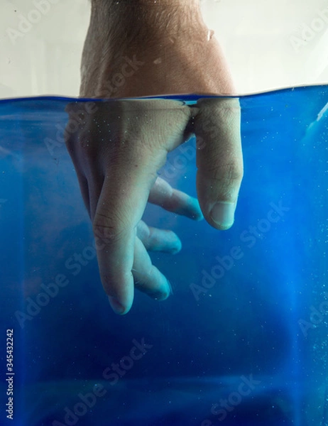 Fototapeta Artistic view of hand under colored water