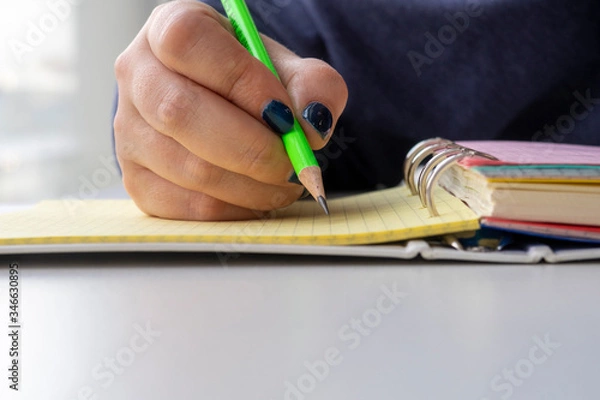 Fototapeta Hand writing with pencil on yellow page in binder notebook.  Taking notes. Copy space for text.