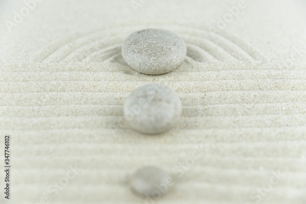 Fototapeta Zen garden. Pyramids of white and gray zen stones on the white sand with abstract wave drawings. Concept of harmony, balance and meditation, spa, massage, relax.