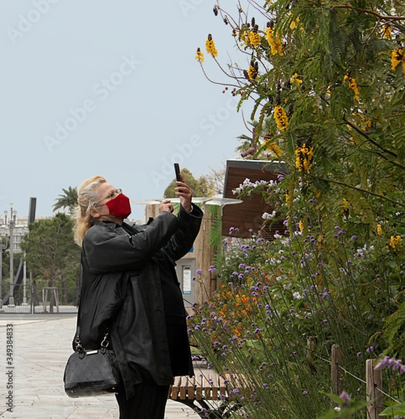 Fototapeta woman walking and wearing red face masks in the park in the  of nice, france