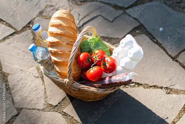 Fototapeta A basket filled with food stands on the floor. Helping poor people during the pandemic