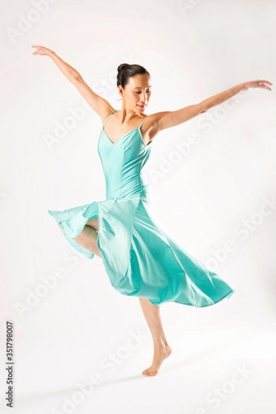 Fototapeta Adult woman dancing in the studio in a blue dress.