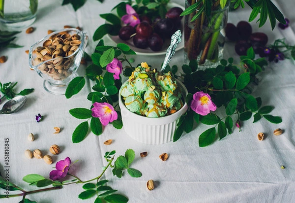 Fototapeta pistachio green ice cream in a white bowl with a spoon on the table