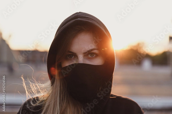 Fototapeta Girl in black medical mask on sunset background.