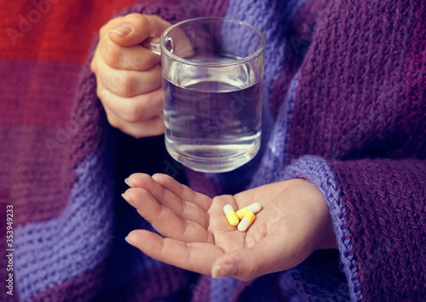 Fototapeta Female hands holding a glass of water and pills