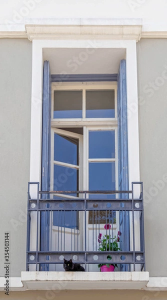 Fototapeta vintage house small balcony with black cat and potted flower in down town Athens, Greece