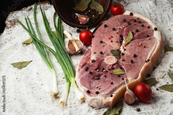 Fototapeta Slices of raw pork knuckle on wooden background. Raw pork meat isolated with vegetables. Advertising for meat shop and farm. Various kinds of meat and ready to cook concept. Top view.